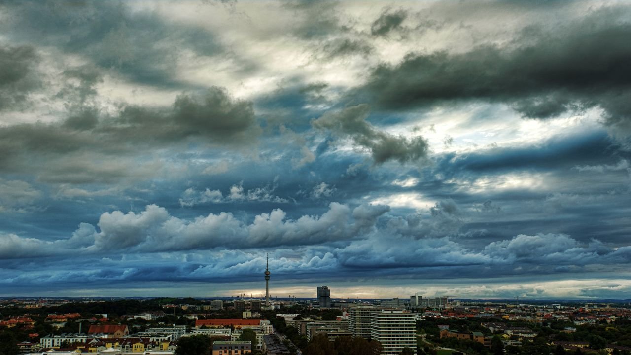 who-we-are A breathtaking view of an urban skyline with dramatic clouds and a distinctive tower.