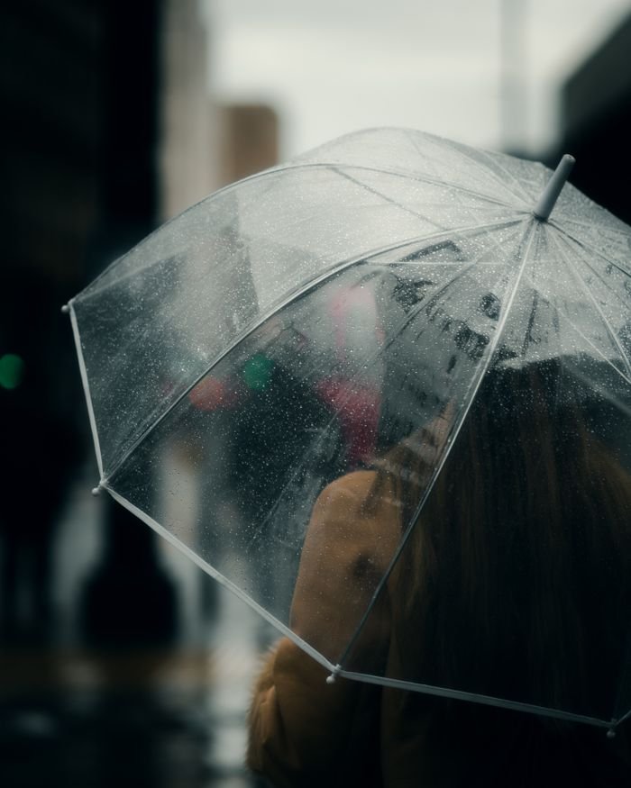 The Art of Drawing Readers In: Your attractive post title goes here A woman walking with an umbrella on a rainy day in Manchester, England.