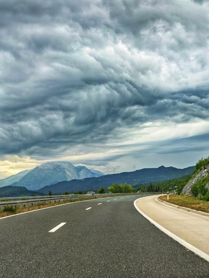 about-us Beautiful Croatian road with stormy sky and mountain in the background.
